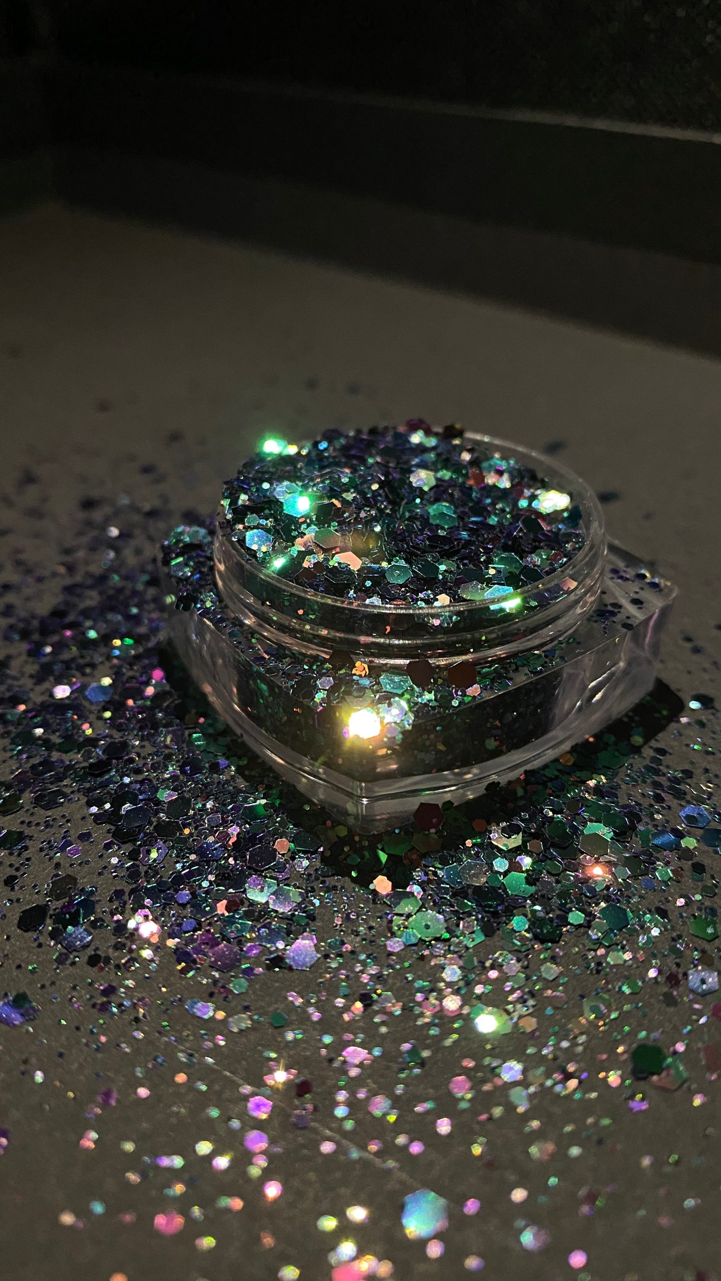 A side view of Beetlejuice Chunky Glitter from DreamSQNS in its component on a black surface