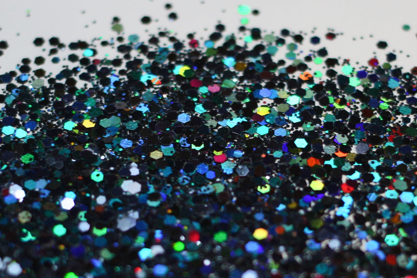 A photo of DreamSQNS Holographic Glitters in shade Black Magic scattered on a white surface